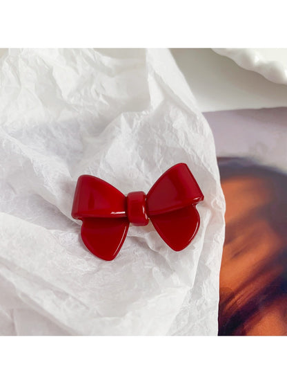 Beau delicate bow hair clip displayed on a wooden surface with natural lighting