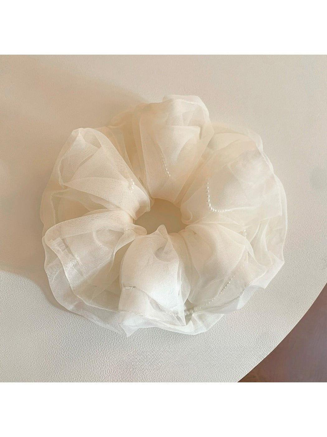 Soft beige tulle scrunchie with elastic band visible inside the fabric folds