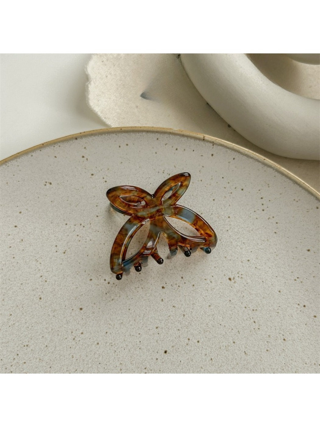 Beau acetate butterfly claw clip placed on wooden surface for styling context