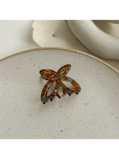 Beau acetate butterfly claw clip placed on wooden surface for styling context
