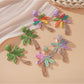 Close-up of Earedge raffia palm tree shaped earrings on white background