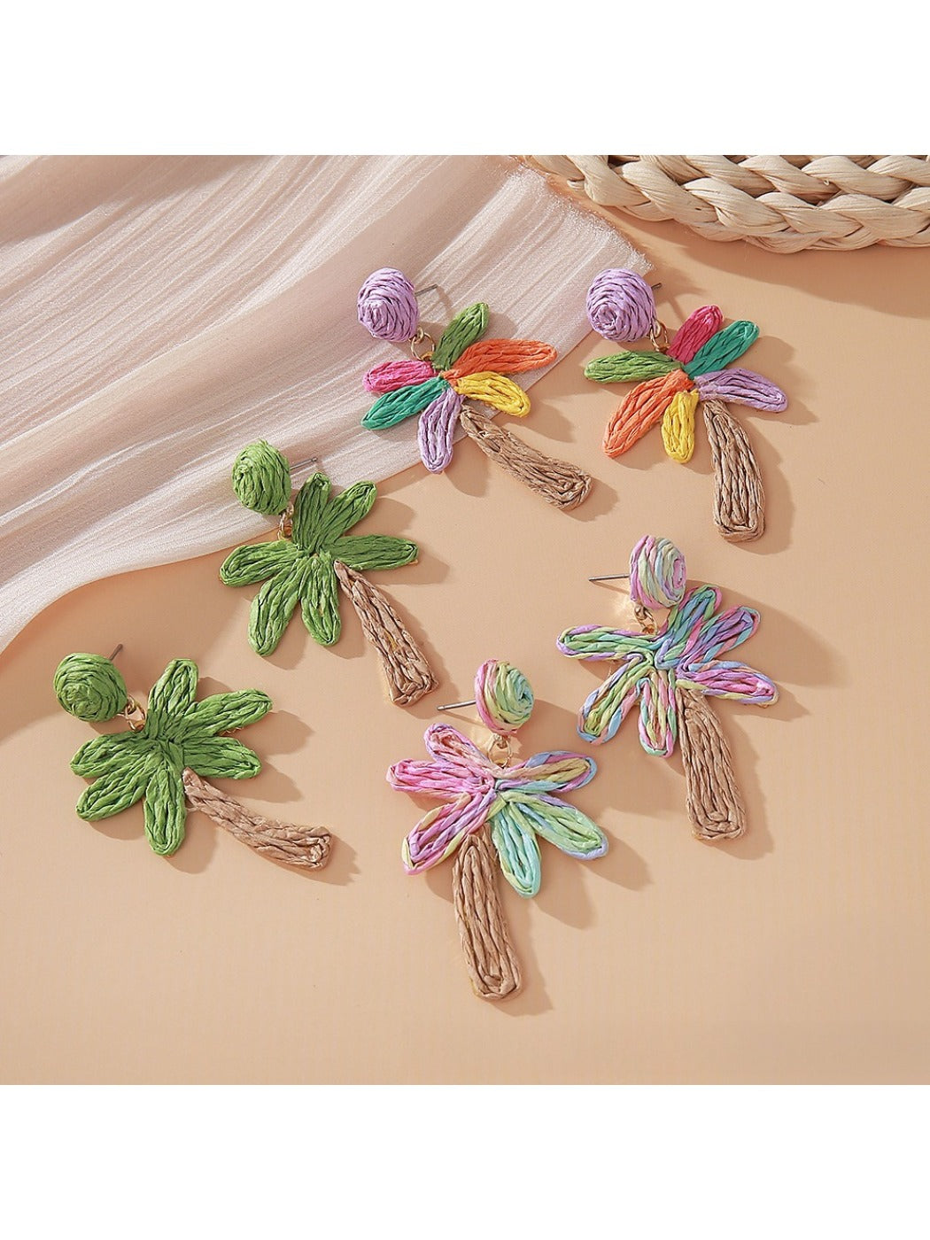 Close-up of Earedge raffia palm tree shaped earrings on white background