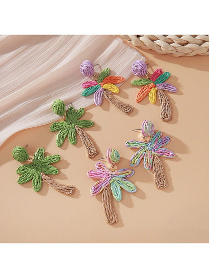 Close-up of Earedge raffia palm tree shaped earrings on white background