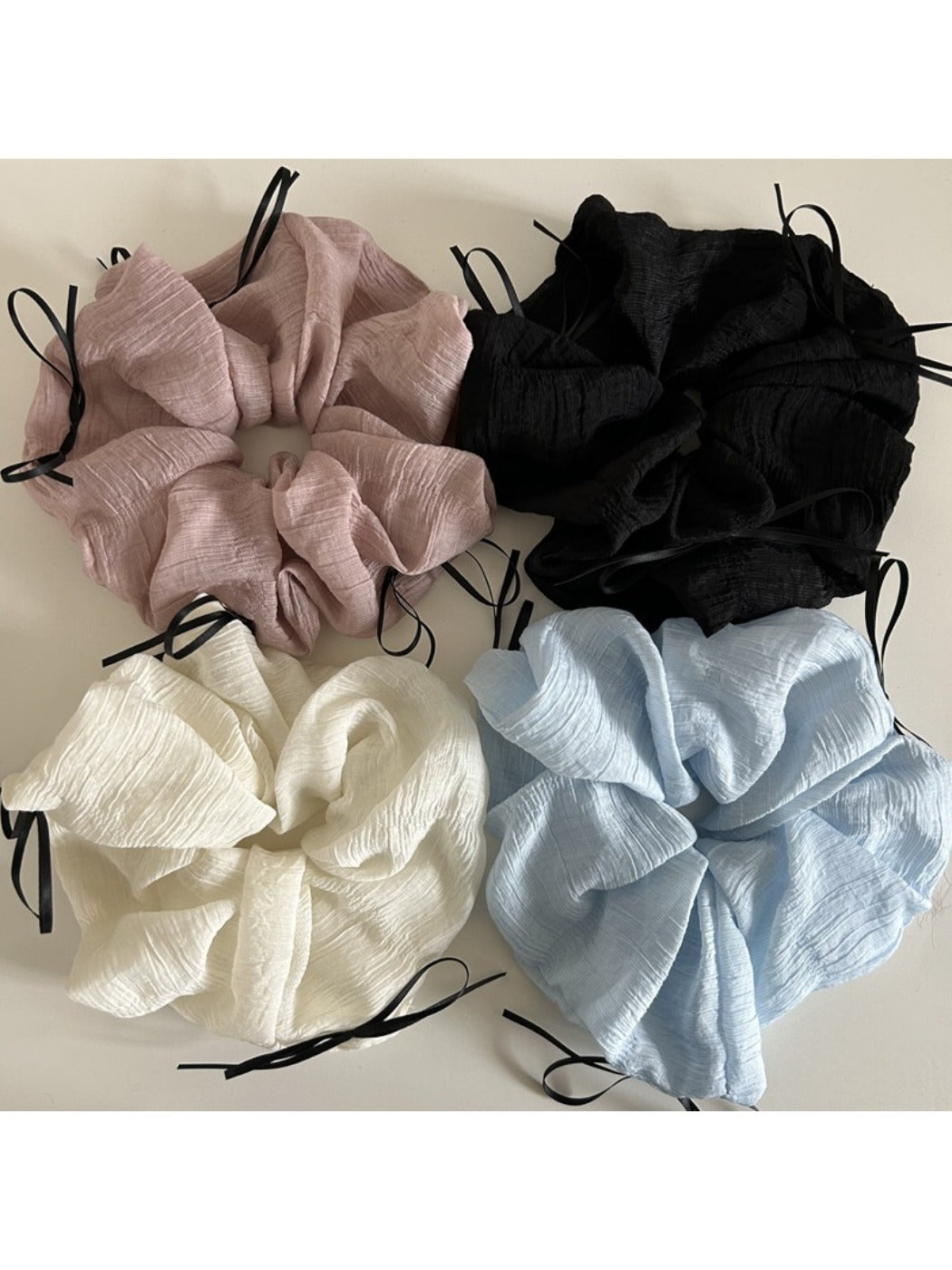 Close-up of a chic ribbon bow tulle scrunchie in soft pink on a white background