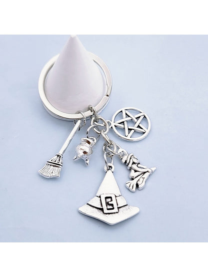 Silver alloy witch hat keychain with broom charm on a wooden surface