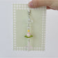 Lotus wind chime keychain hanging from a bag strap outdoors