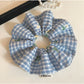 Blue plaid scrunchie wrapped around a ponytail in brown hair