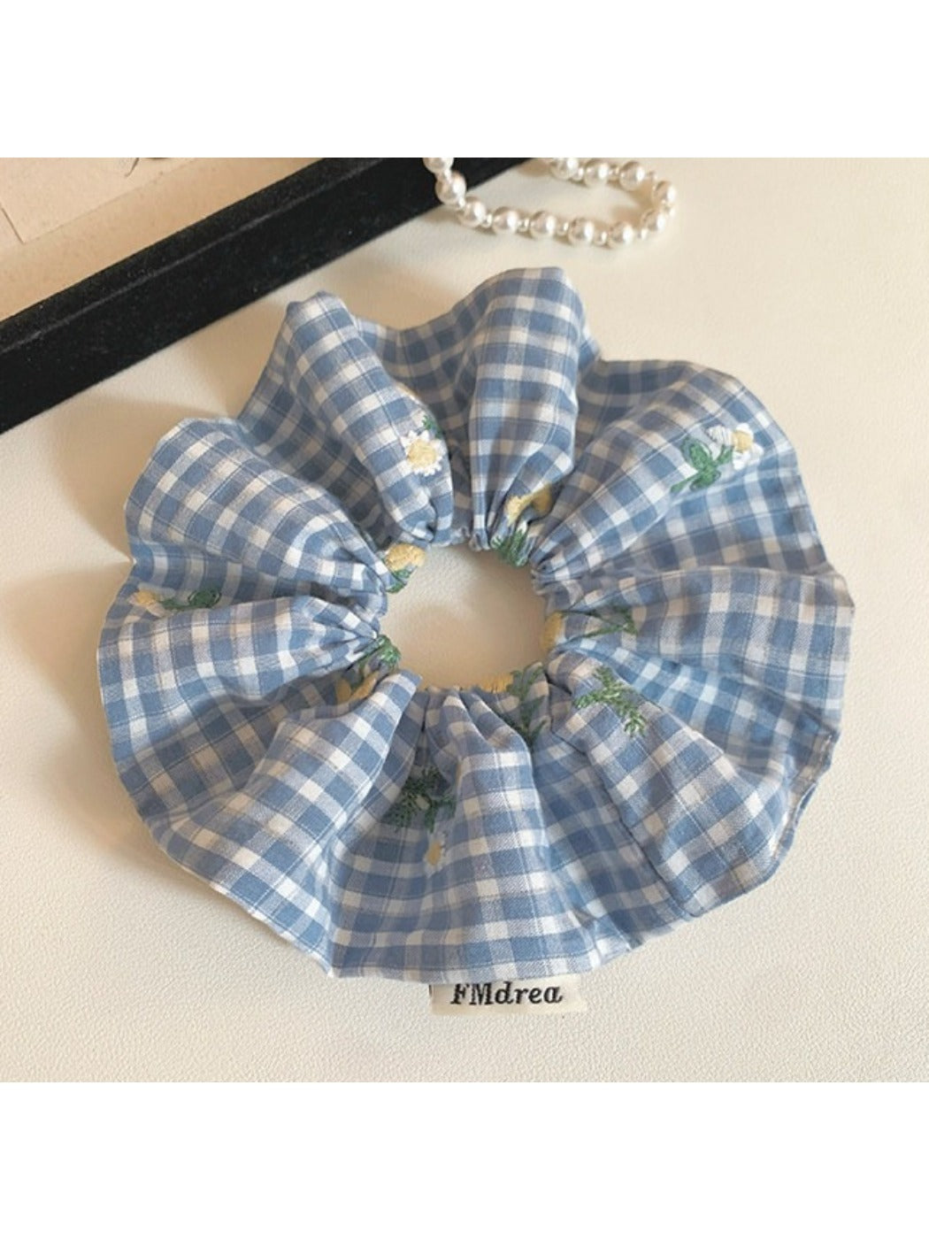 Blue plaid scrunchie wrapped around a ponytail in brown hair