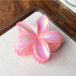 Beau flower shaped claw clip placed on a light neutral background