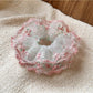 Pink scrunchie with layered ruffles displayed on a white background