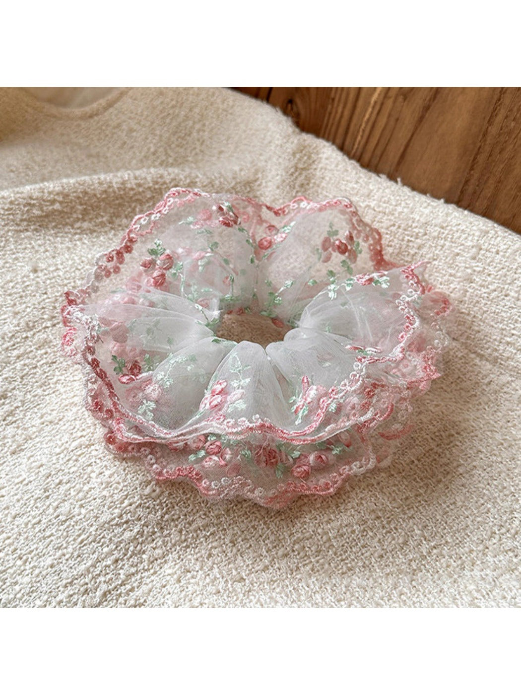 Pink scrunchie with layered ruffles displayed on a white background