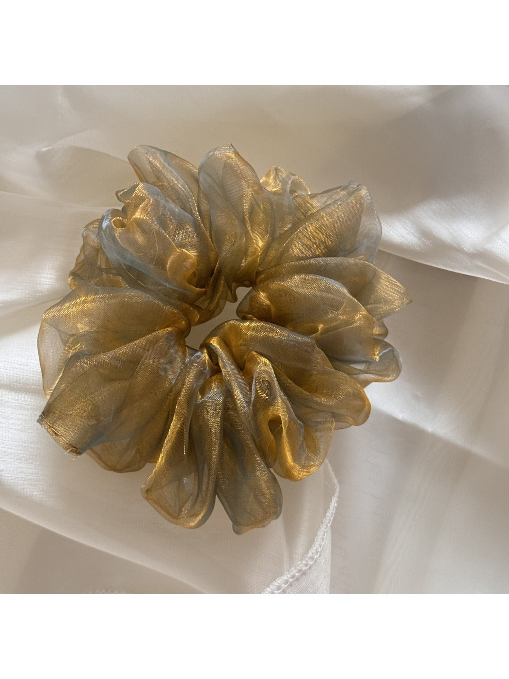 Close-up of iridescent organza fabric scrunchie showing texture and colors