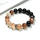 Lovra Crystal Obsidian Beaded Bracelet displayed on a wooden surface showing bead texture and shine