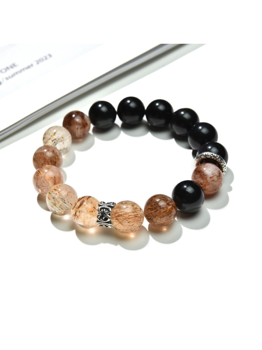 Lovra Crystal Obsidian Beaded Bracelet displayed on a wooden surface showing bead texture and shine