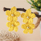 Close-up of gold hooks attached to raffia flower shaped earrings