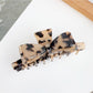 Beau bow shaped claw clip resting on a wooden surface