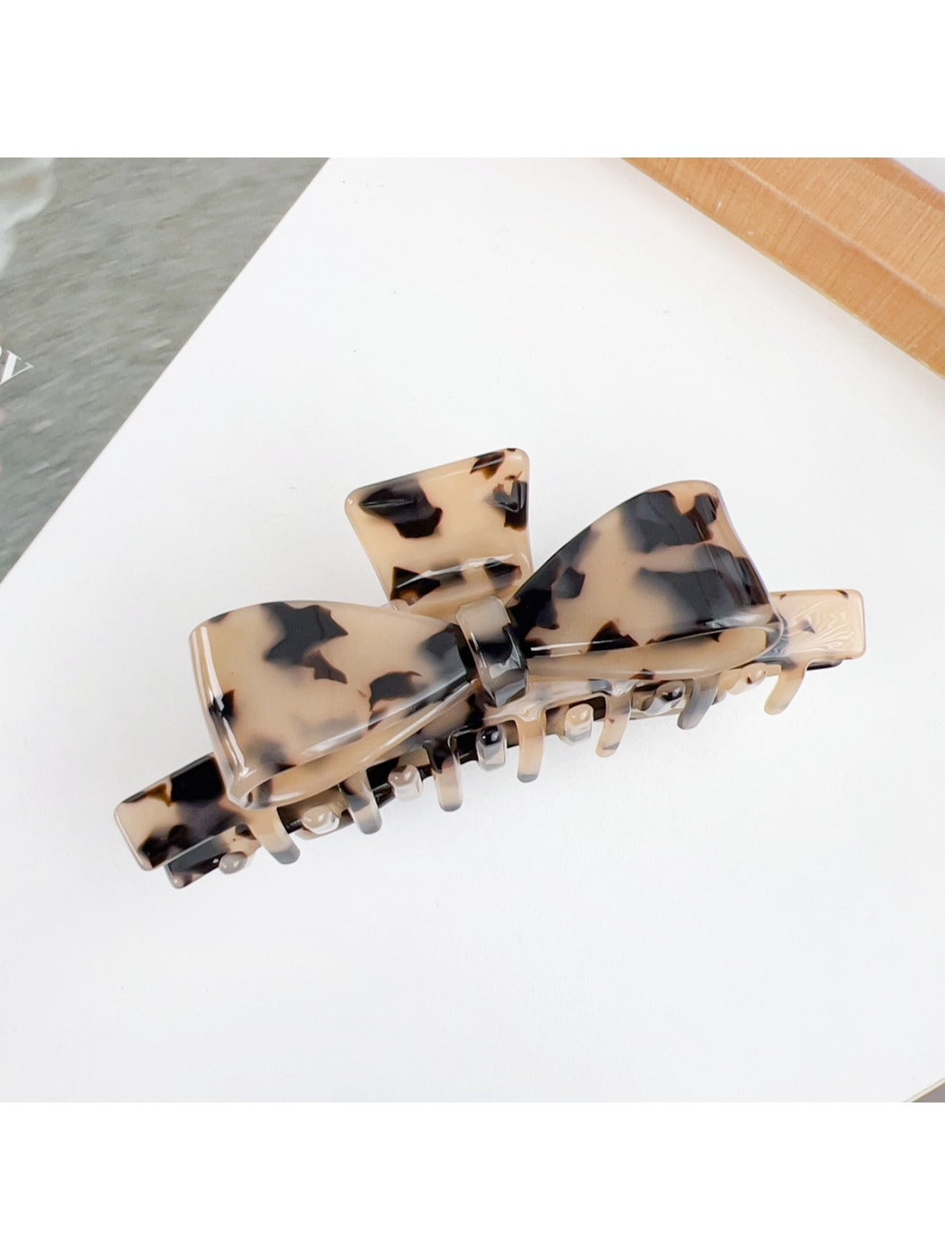 Beau bow shaped claw clip resting on a wooden surface