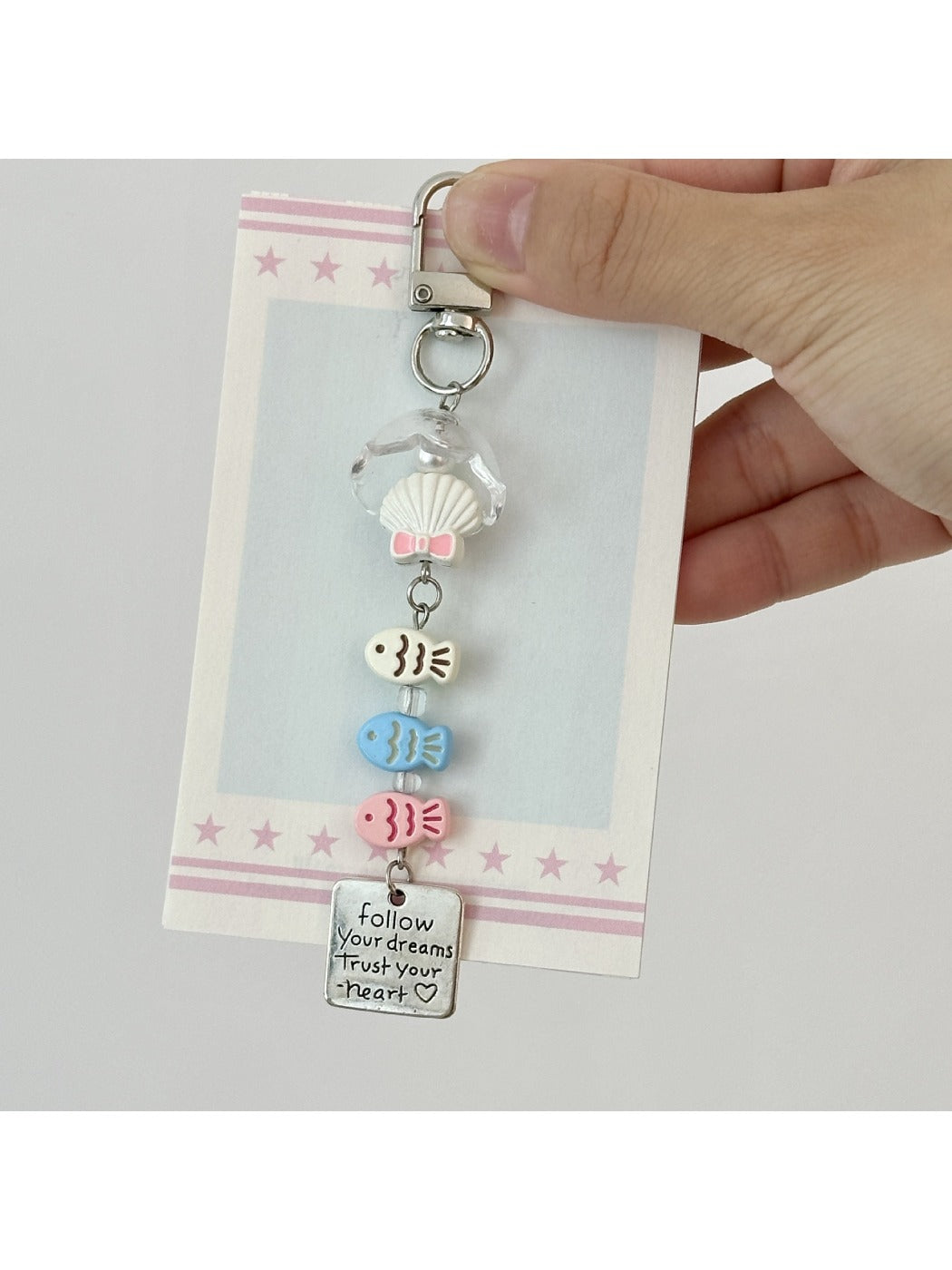Three pastel fish-shaped keychains displayed on a white surface with shadows