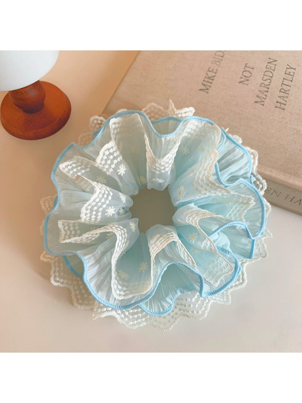 Close-up of a blue lace scrunchie with delicate floral patterns