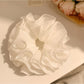 Close-up of elegant white ruffled scrunchie made of soft fabric