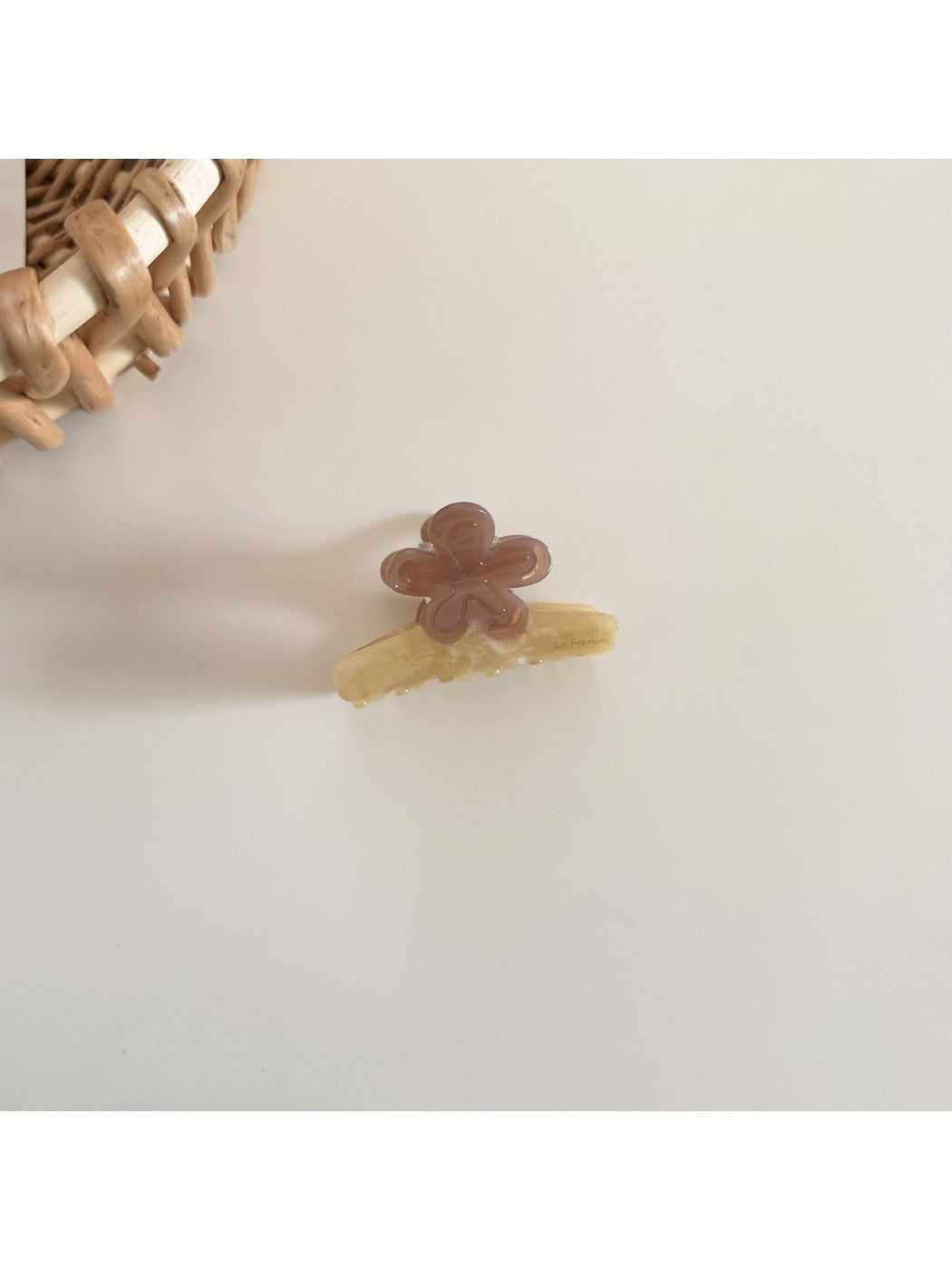 Beau acetate flower hair clip in soft pastel colors placed on a wooden surface