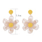 Earedge raffia flower drop earrings displayed on a beige fabric surface