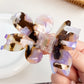 Top view of flower-shaped hair claw clip displaying symmetrical colorful petals