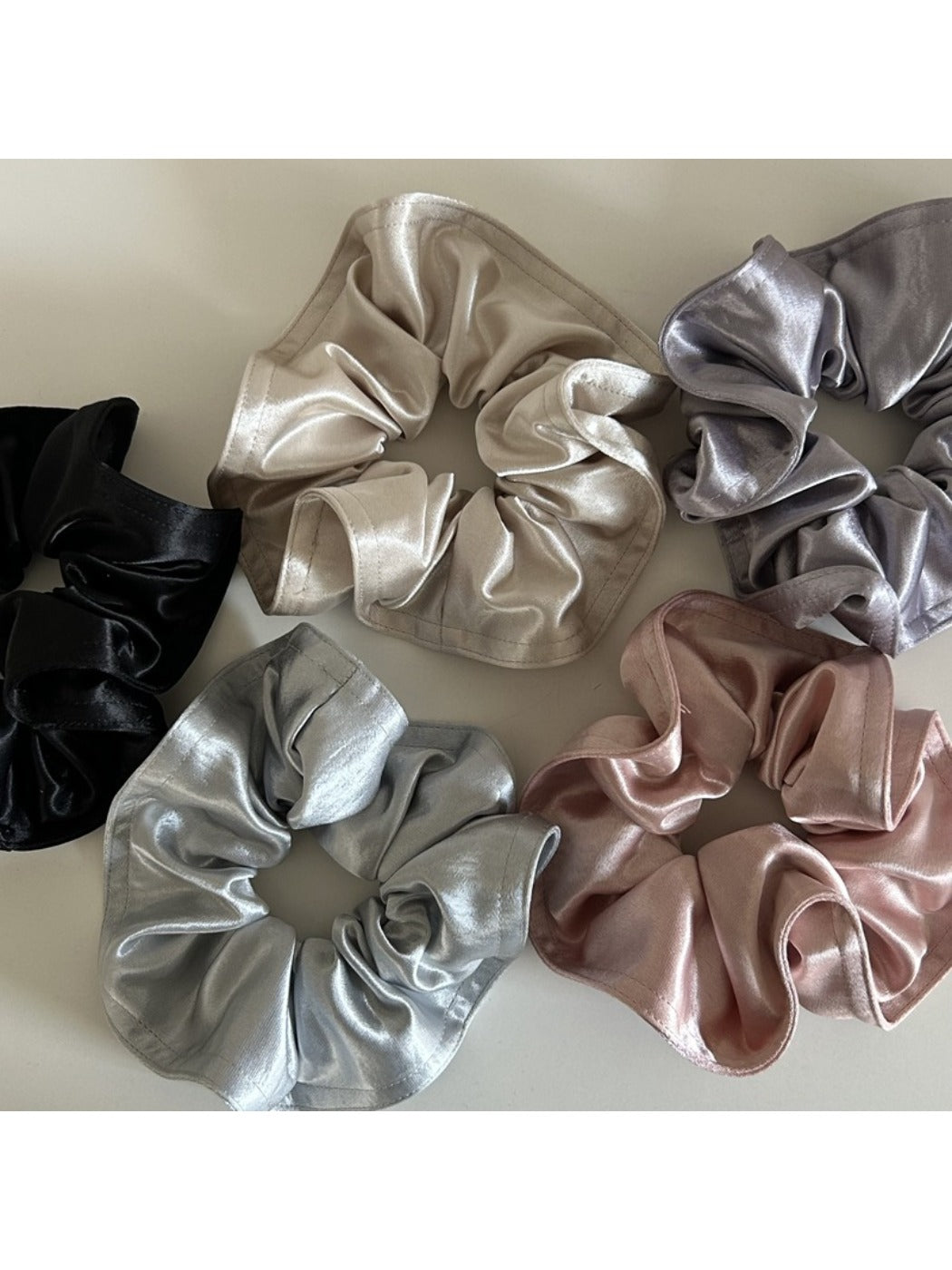 Gifty satin scrunchie wrapped around a ponytail on a model with dark hair