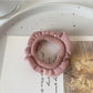 Ruffled hair ties in multiple colors arranged in a fan shape on a white surface