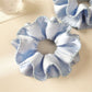 Close-up of blue satin scrunchie showing layered design and stitching details