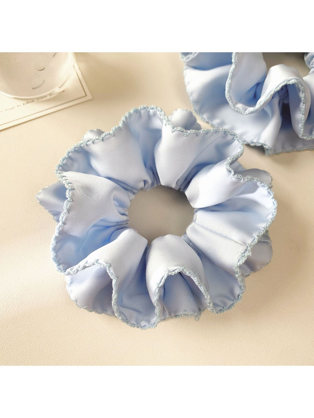 Close-up of blue satin scrunchie showing layered design and stitching details
