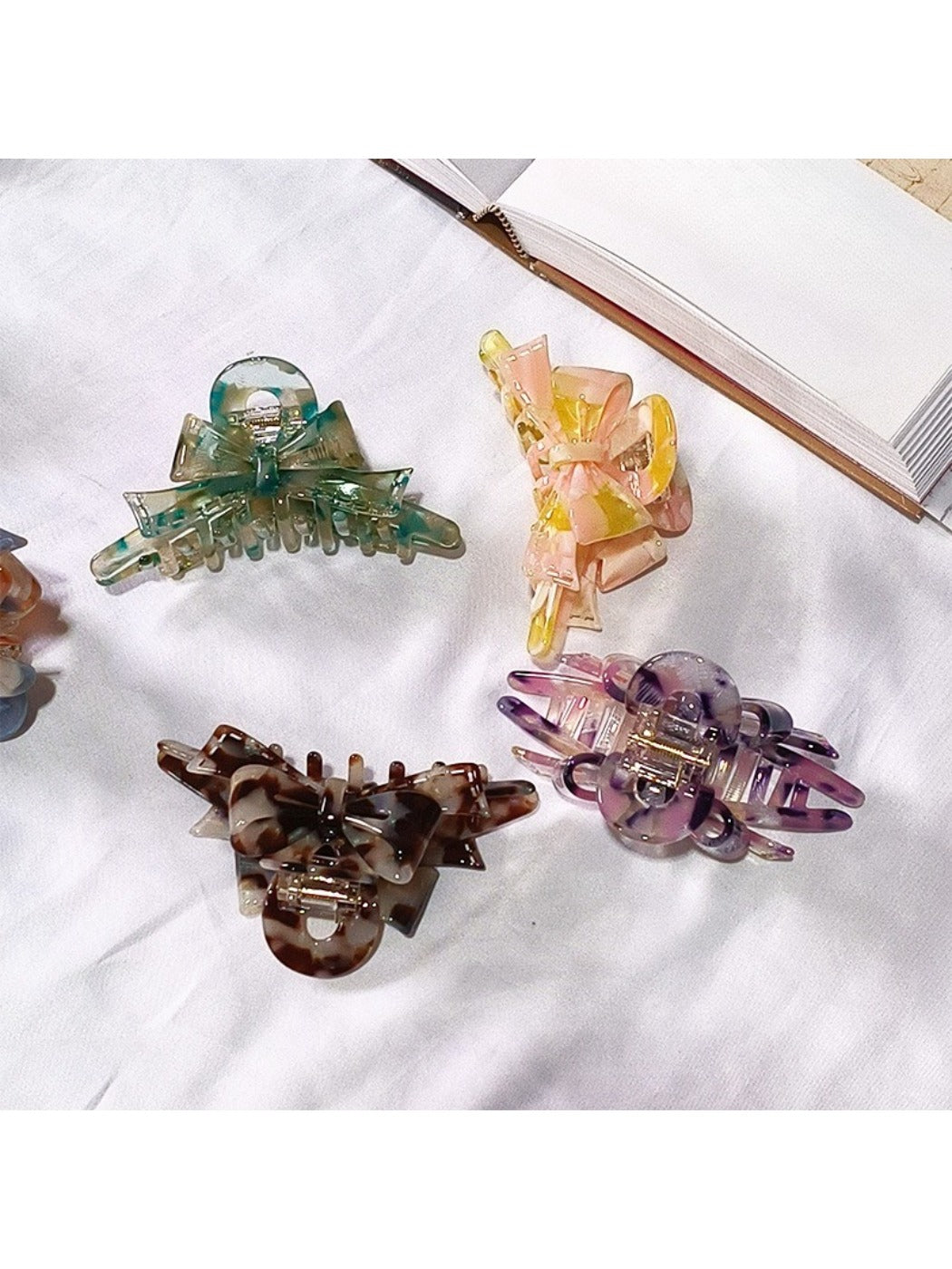 Beau acetate bow shaped claw clip held in hand showing size and scale