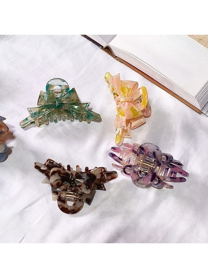 Beau acetate bow shaped claw clip held in hand showing size and scale