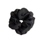 Close-up of beige tulle scrunchie featuring white polka dots and gathered fabric texture