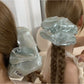Side view of a ruched satin scrunchie showing smooth fabric and elastic band