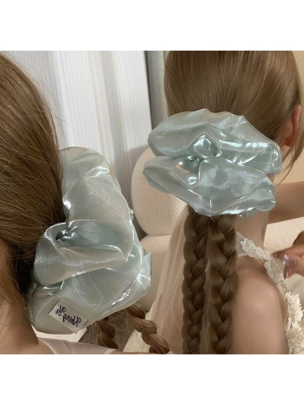 Side view of a ruched satin scrunchie showing smooth fabric and elastic band