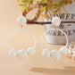 Pair of Earedge raffia round ball earrings on a wooden surface