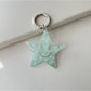 Silver star keychain attached to a set of house keys on a wooden table