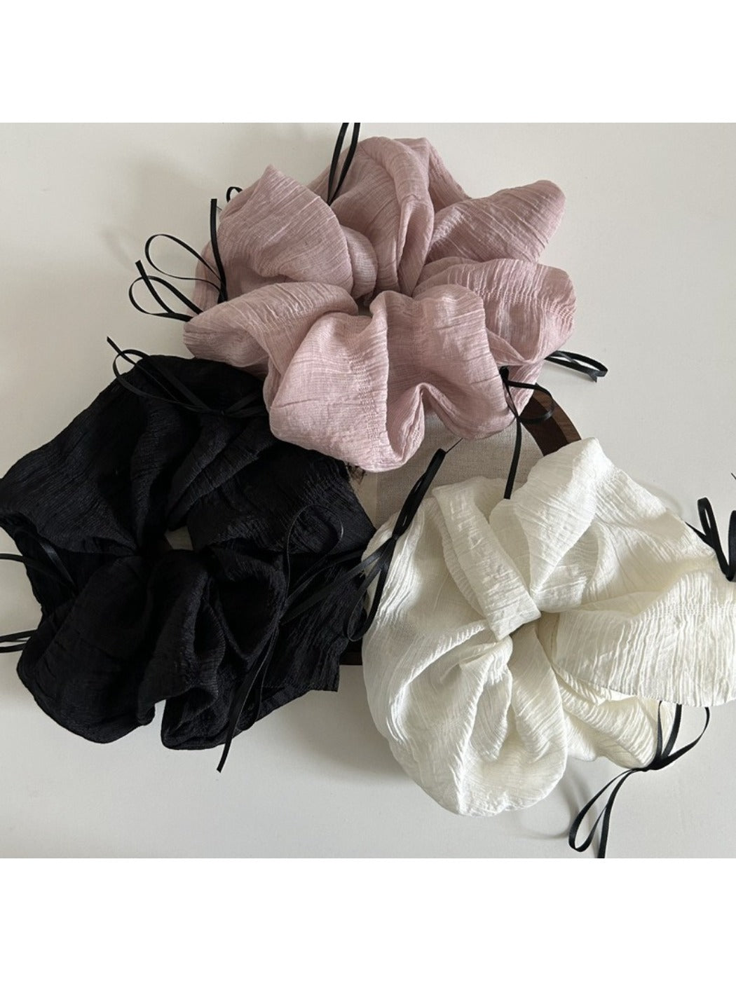 Side view of a pink tulle scrunchie with a large decorative ribbon bow
