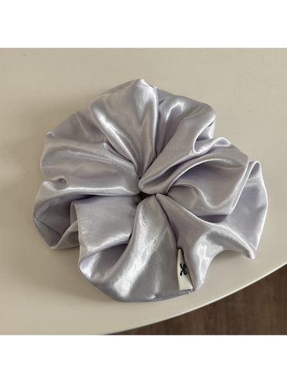 Glossy satin scrunchie in pink with light reflecting off smooth fabric