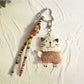 Cat charm keychain hanging from a backpack zipper in outdoor setting