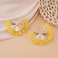 Earedge raffia woven fan shape earrings displayed flat on textured fabric