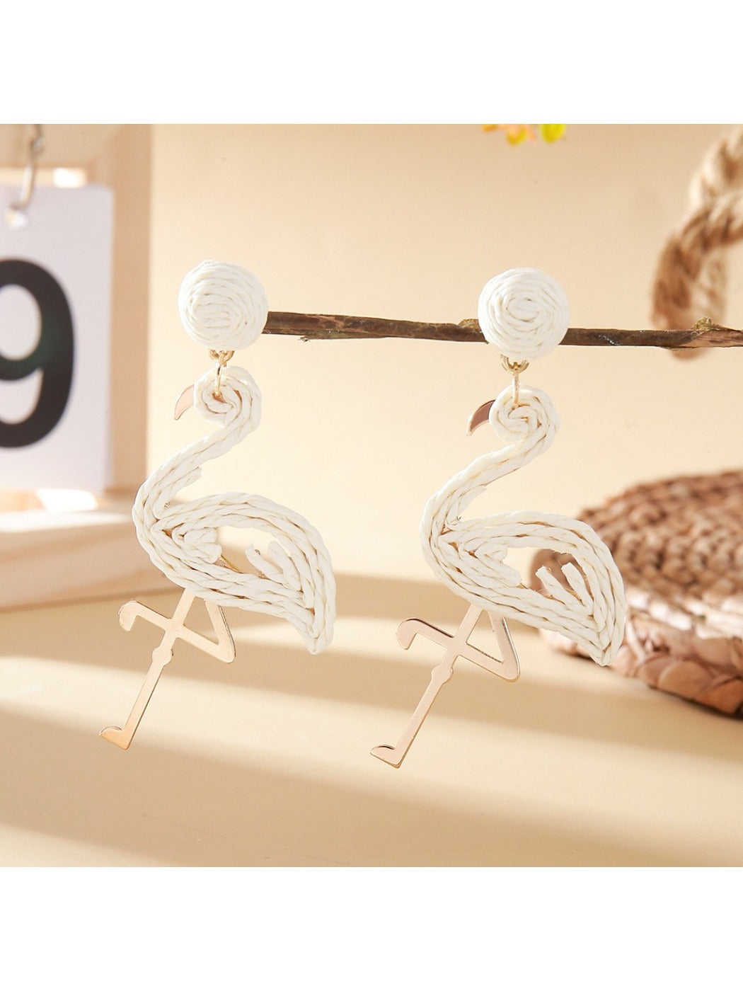 Flamingo pendant earrings worn on a model's ear with a blurred background