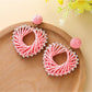 Pair of silver heart-shaped drop earrings resting on a velvet cloth