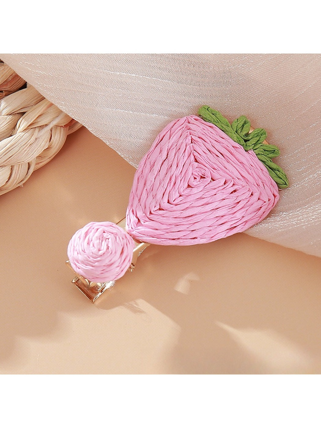 Beau raffia strawberry flower hair clip next to natural raffia strands