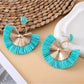 Pair of raffia fan earrings with light brown woven design and gold accents