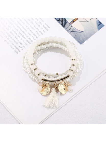 Lovra beaded bracelet wrapped around a wrist with metal tassel pendant