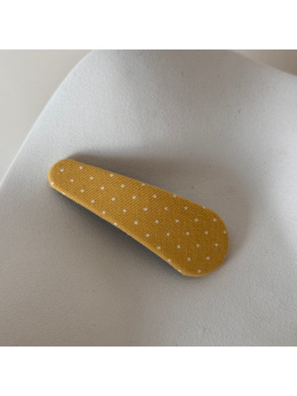 Beau polka dot hair clip on a wooden surface with soft lighting