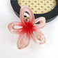 Beau classic flower hair claw clip held in hand showing size and detail