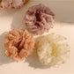 Close-up of Gifty vintage scrunchie with multicolored bead accents on beige fabric